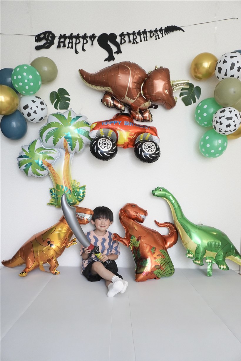 黒い恐竜の骨格デザインのHAPPY BIRTHDAYガーランドと、濃いグリーン・くすみグリーン・牛柄・緑ドットのゴム風船