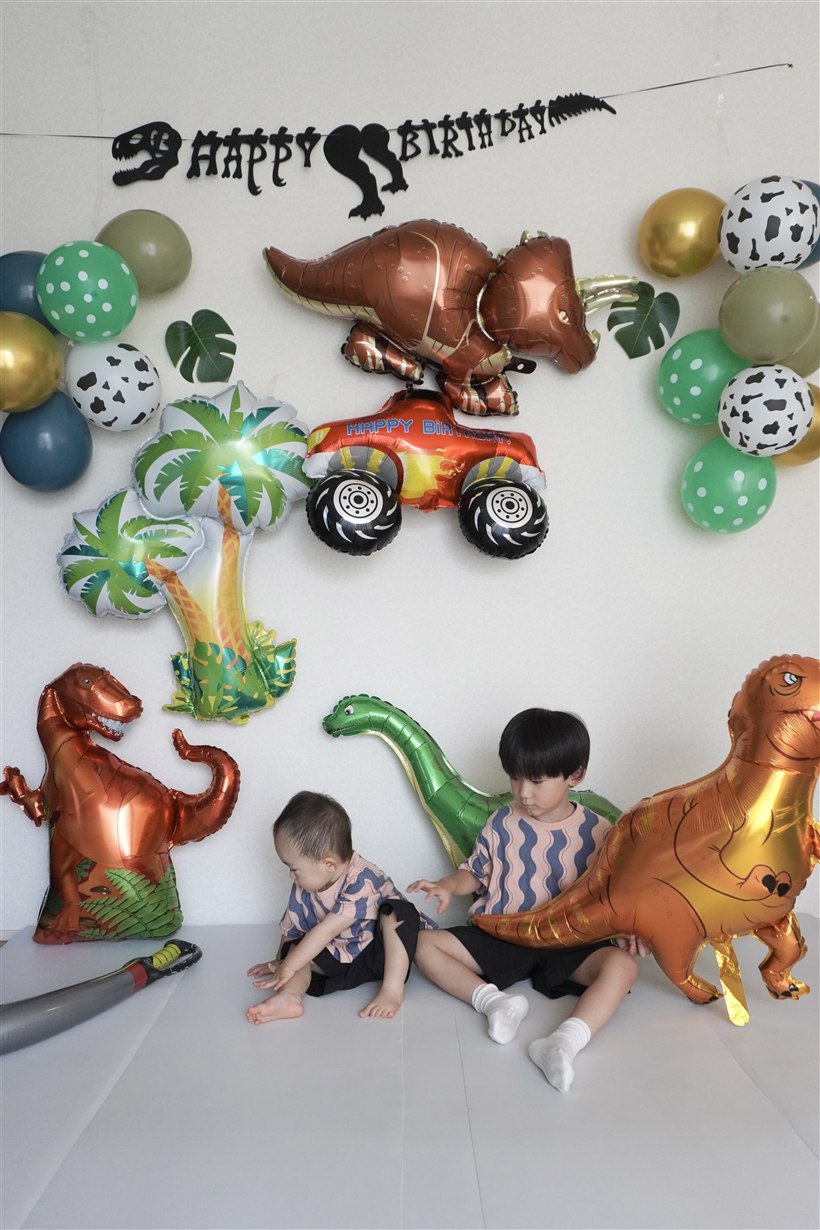 お兄ちゃんと下の子のきょうだいが並んで、恐竜バルーンと写る誕生日の実例