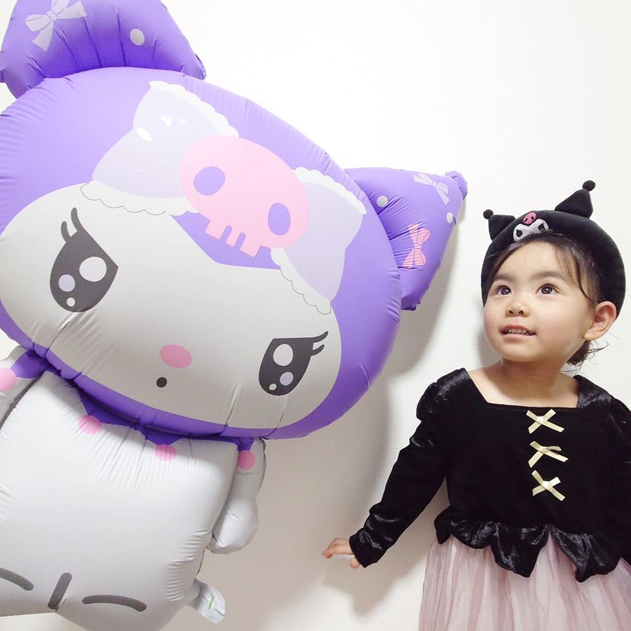 白い壁を背に飾った特大のクロミのバルーンと、クロミのカチューシャをつけて見上げている子ども
