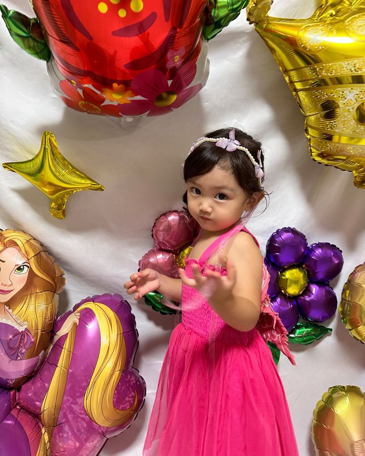 ラプンツェルのバルーンと、大きな赤い花・紫の花・ゴールドの王冠のバルーンにかこまれたお子さま