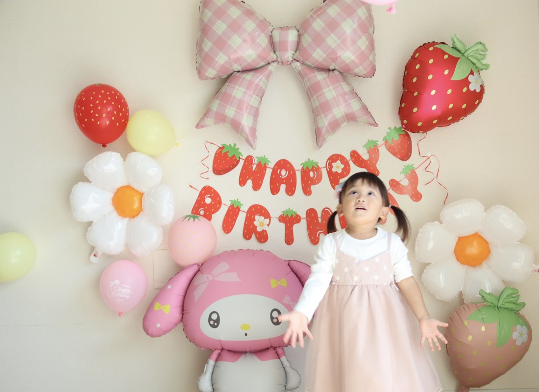 いちごマイメロの飾り付けの前で、ピンクのチュールスカートと白い長袖のお子さまが両手を広げて上を見上げている