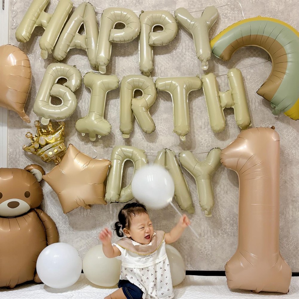 くすみカラーの誕生日飾り付けの前で笑う1歳の赤ちゃんの実例
