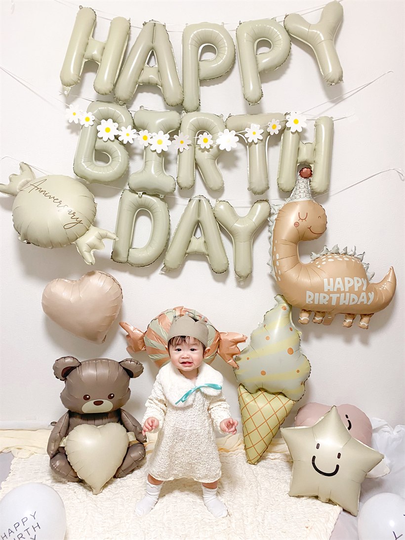 くすみカラーの誕生日飾り付けの前で笑顔で立つ2歳の女の子の実例