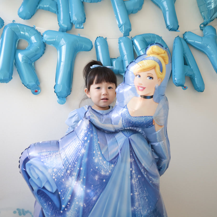 水色の服の女の子がシンデレラのバルーンにぎゅっと寄り添っている実例写真