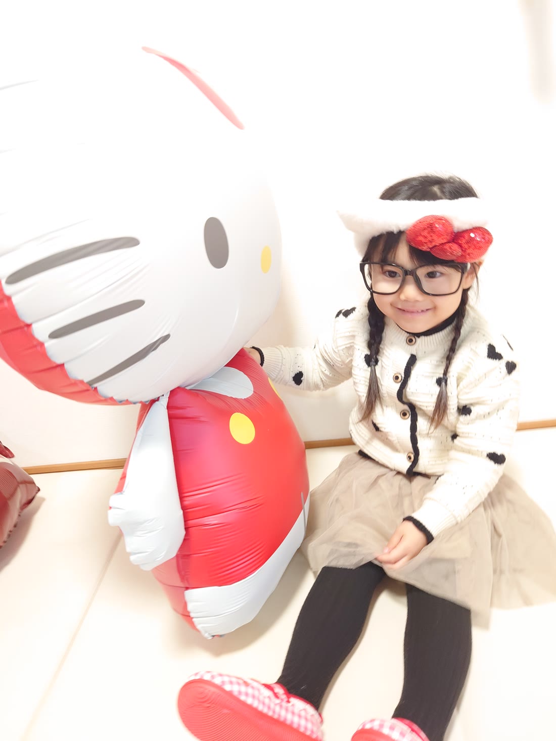 特大ハローキティバルーンに寄り添って笑う女の子のクローズアップ