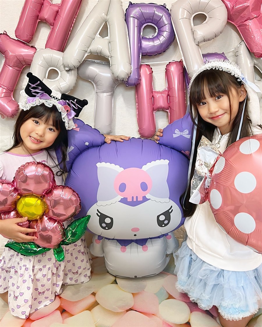 HAPPY BIRTHDAYの文字バルーンと特大クロミバルーンを囲む姉妹。フラワーバルーンと水玉バルーンも