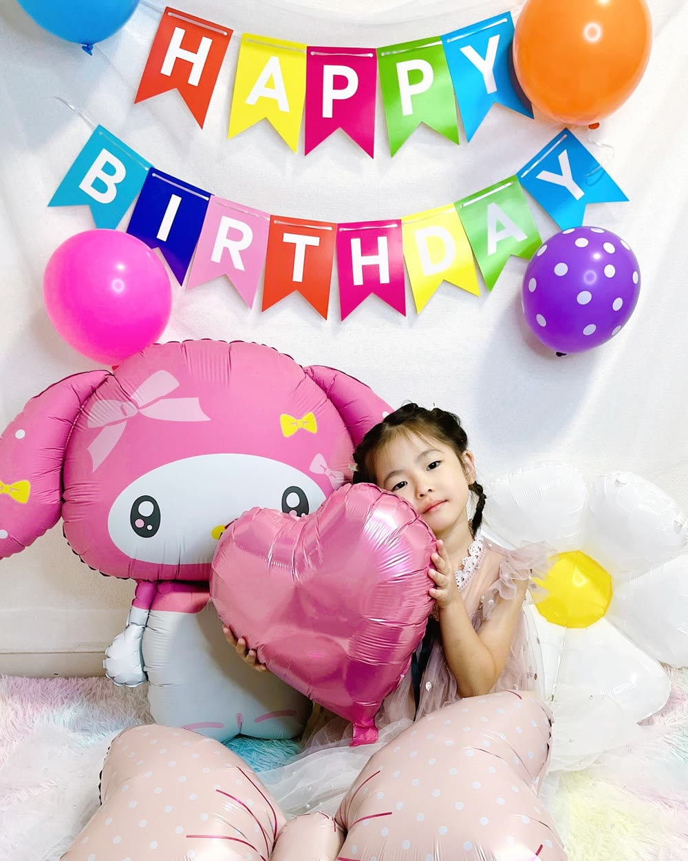 HAPPY BIRTHDAYガーランドとカラフルなゴム風船、特大マイメロディバルーンとハートバルーンで飾った誕生日。女の子がハートを抱えている