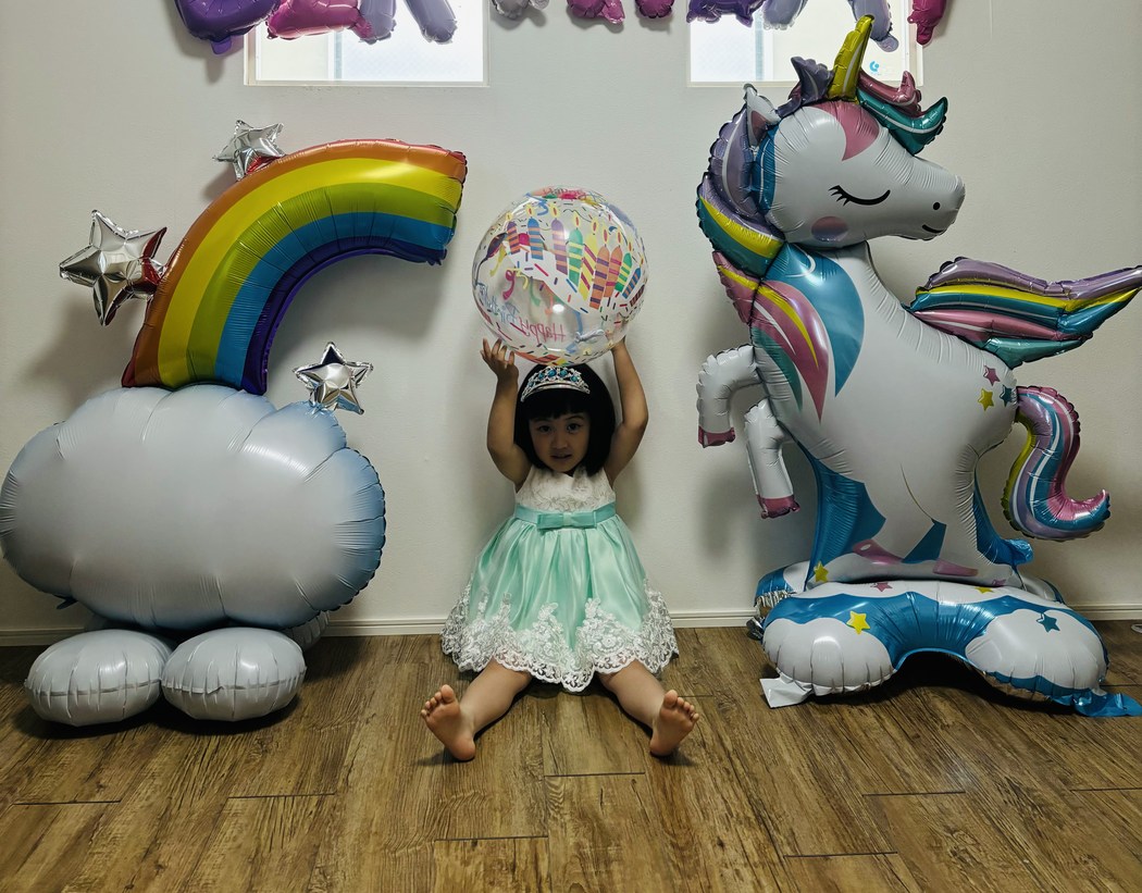 ユニコーンのバルーンと座っている子どもを並べた実例写真。ユニコーンのほうが背が高い
