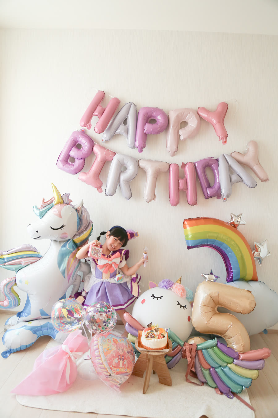 プリキュアの衣装を着た5歳の女の子が、大きなユニコーンバルーン・虹・数字5のバルーン・ボールユニコーンに囲まれている誕生日の実例写真