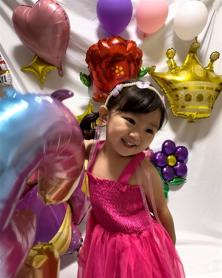 ラプンツェルのバルーンと一緒に写る女の子のバースデーフォト。淡い色でまとめ、一部を切り取った構図